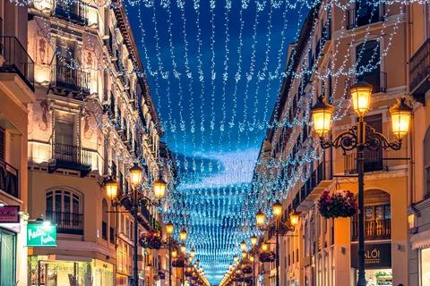 Bright strings of holiday lights create a glowing tunnel at night in Zaragoza Stock-Fotos