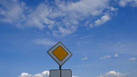 Bright summer scene with a priority road sign standing tall against a dynam.. Stockfoto's