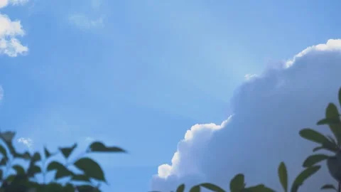 Bright summer sunlight streaming through white fluffy clouds in a clear blue sky 動画素材 341955349