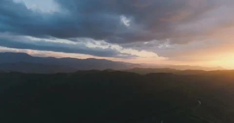 Bright sun beams piercing sky, clouds and lighting hillside. Green hills and Stock Footage 131028560