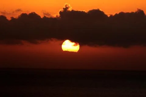 The bright sun between clouds during a nice sunset in Oia, Santorini Stock Photos