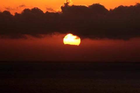 The bright sun between clouds during a nice sunset in Oia, Santorini Stock Photos