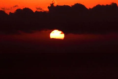 The bright sun between clouds during a nice sunset in Oia, Santorini Stock Photos