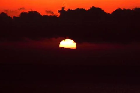 The bright sun between clouds during a nice sunset in Oia, Santorini Stock Photos