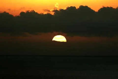 The bright sun between clouds during a nice sunset in Oia, Santorini Stock Photos