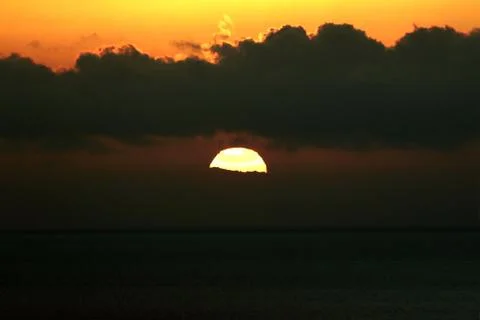 The bright sun between clouds during a nice sunset in Oia, Santorini Stock Photos