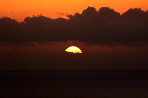 The bright sun between clouds during a nice sunset in Oia, Santorini Stock Photos