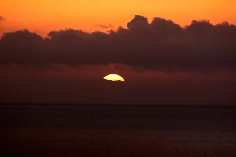 The bright sun between clouds during a nice sunset in Oia, Santorini Stock Photos