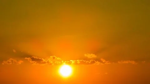 Bright sun casts rays through clouds, illuminating an intensely orange and .. Stock Photos