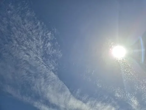 Bright sun in a cloudy blue sky 库存照片