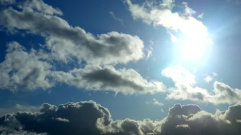 The bright sun creates rays through massive clouds in the blue sky Stock Footage 134903123