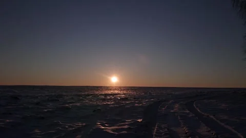 Bright sun on dark blue sky setting over snow field at sunset Stock Footage 303336545