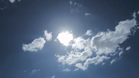 Bright sun emerging from behind white fluffy clouds in blue sky Stock Footage 115760512