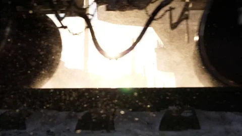 Bright sun flash between wheels of running cargo train, low camera, snow fly Stock Footage 84268204
