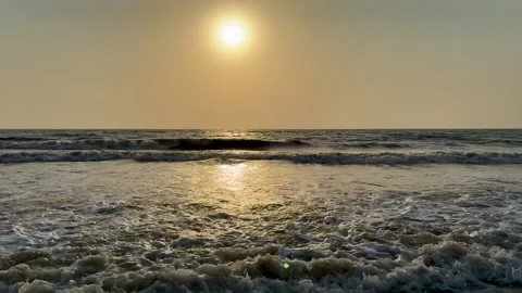 Bright sun glowing over parallel ocean waves on sandy beach at sunset Vídeos de archivo 336623786