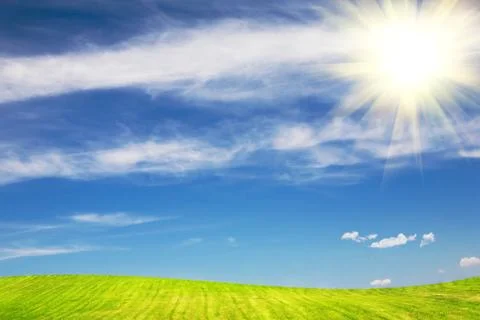 Bright sun, green fields, blue sky in summer Stock Photos