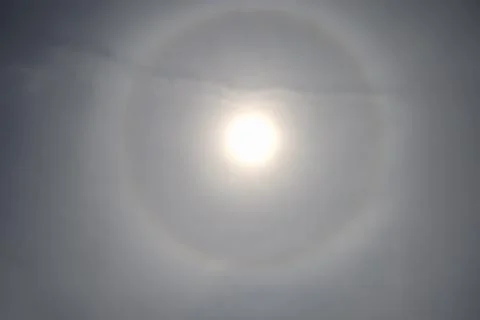 Bright sun halo through thin clouds creating atmospheric sky effect Stock Photos