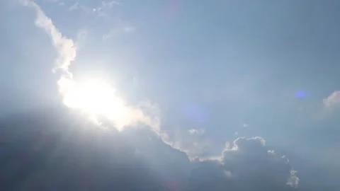 Bright sun light ray flare shining through dark storm cloud on blue sky Stock Footage 183319618