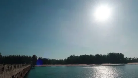 Bright sun light ray n sunbeam flare over summer beach with fishing bridge Stock Footage 148311886