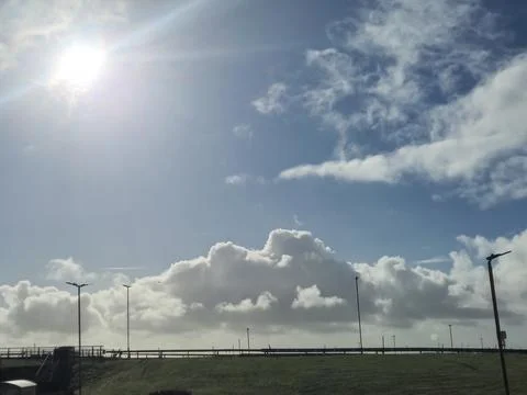 Bright sun over cloudy sky above roadside landscape Stock Photos