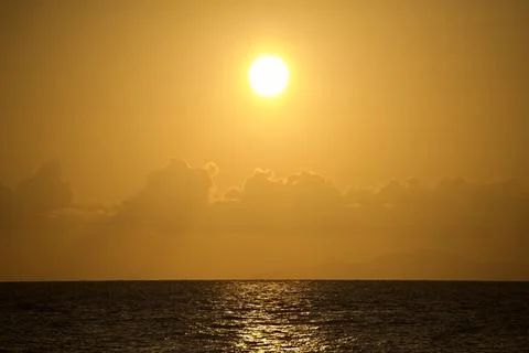 Bright Sun Over Ocean Beneath Warm Golden Sky Stock-Fotos