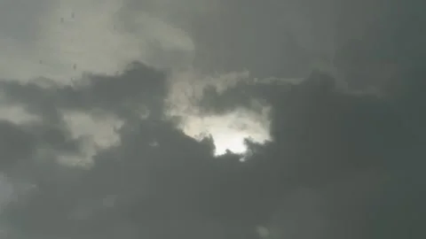 Bright sun peeking from behind a large dark storm cloud Stock Footage 338365125