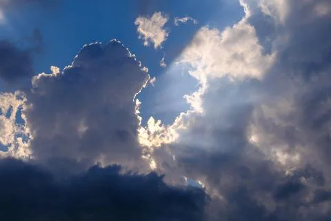 Bright sun rays breaking through beautiful clouds in the blue sky Photos