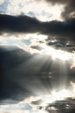 Bright sun rays coming through the clouds and falling on sea water Stock Photos