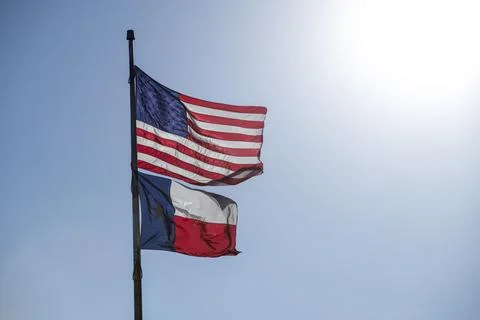 Bright Sun Rays Shining US American and Texas Flags on Pole Outside Stock Photos