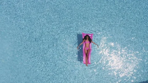 Bright Sun Reflecting on Pool Waters and Sexy Lady Relaxing on Floatie Video stock 138180516