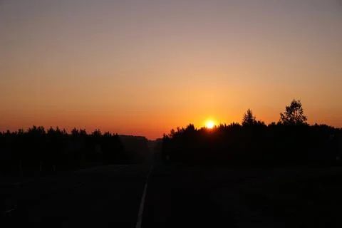 Bright sun rises over the forest and road Stock Photos