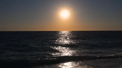 Bright sun rising or setting over a dark ocean with golden light. 스톡 동영상 347228352