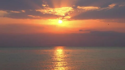 Bright sun rising over a calm sea, orange sky with reflection on water Stock Footage 317549705