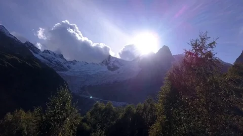Bright sun sets behind the mountain. The sun's rays illuminate the tops of trees Stock Footage