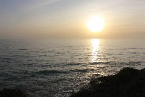 Bright sun setting on calm ocean creating golden reflection on water surface Stock Photos