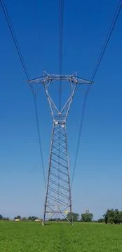 The bright sun shines down through power lines in an open field Stock Photos