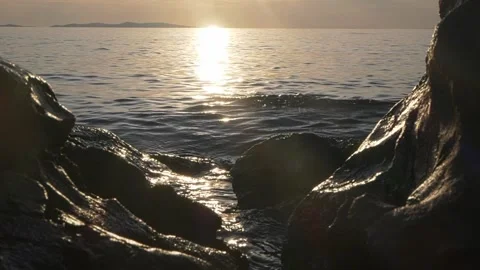 Bright sun shining over ocean waves framed by dark rocks Stock Footage 337415227