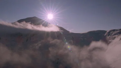 Bright sun shining over a snowy mountain peak Stock Footage 335106039
