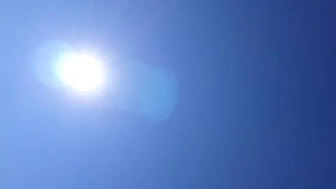 Bright sun shining through a clear blue sky with lens flare Stock Photos