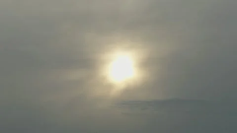 Bright sun shining through dark dramatic clouds over tree silhouettes Stock Footage 338201089