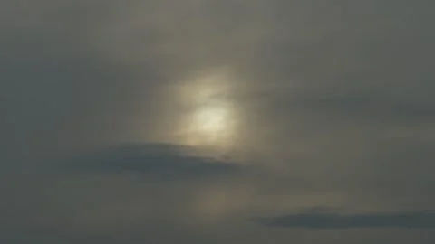 Bright sun shining through dark dramatic clouds over tree silhouettes Stock Footage 338201323