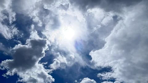 Bright sun shining through dramatic white cumulus clouds in a deep blue sky Stock-Fotos