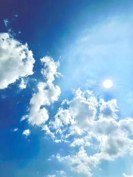 Bright Sun Shining Through Fluffy White Cumulus Clouds in Clear Blue Sky Stock Photos