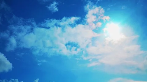 Bright sun shining through white clouds in deep blue sky Stock Footage 332225215