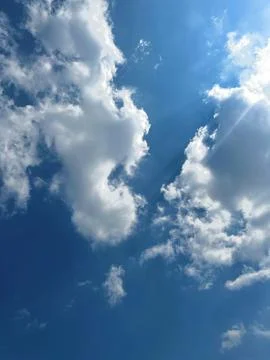 Bright Sun Shining Through White Fluffy Clouds in a Beautiful Clear Blue Sky Stock-Fotos
