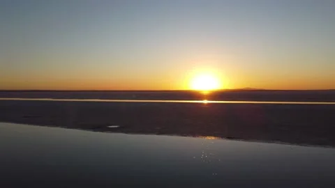 Bright sun shining while flying low towards it over flat salt lake Tuz Stock Footage 169477110