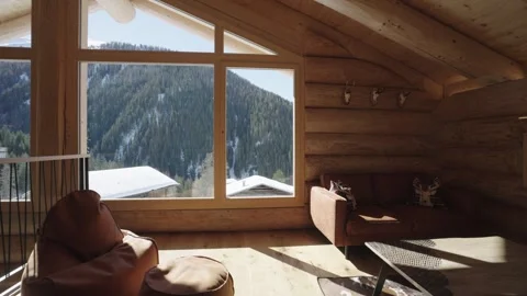 Bright sunbeam moving inside a cozy log cabin living room with a snowy mountain Stock Footage 335757177