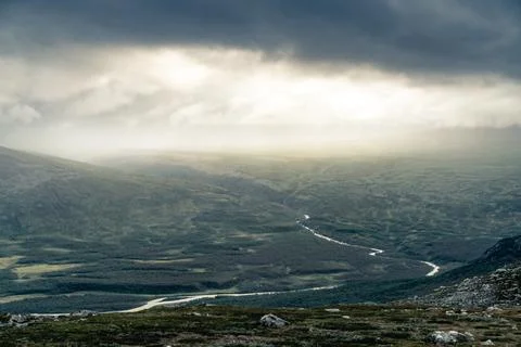 Bright sunlight comes through thick clouds and illuminates heavy rainfall in the Stock Photos