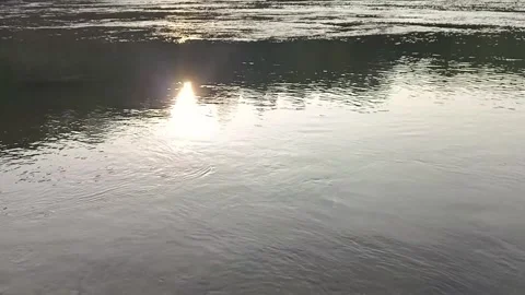 Bright sunlight creates a warm flare and shimmering reflection across calm w Stock Footage 342954246