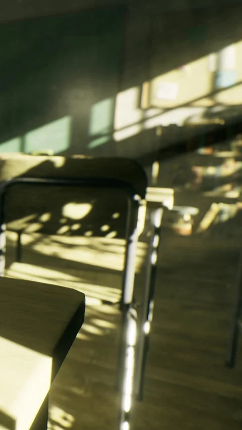 Bright sunlight dances across empty classroom desks in quiet afternoon light Stock Footage 334246826